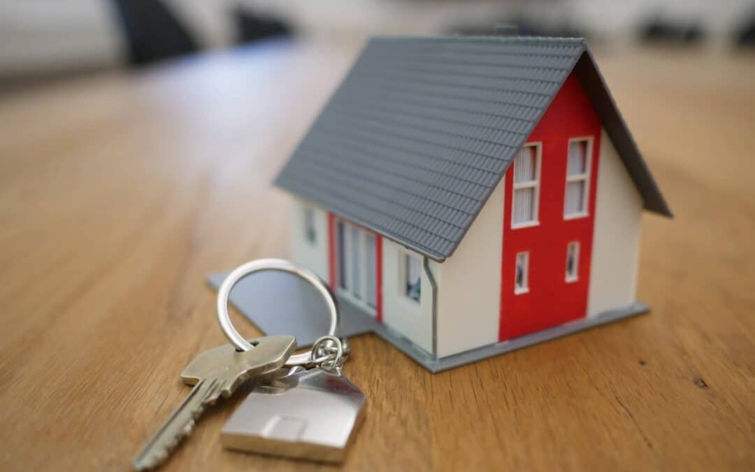 a key on a house shaped keychain with a toy house sitting next to it