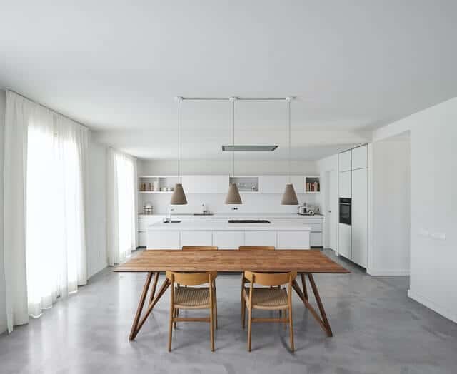 An example of an open floor plan concept showing an open kitchen and dining area. A wooden dining set with four chairs is at the forefront.