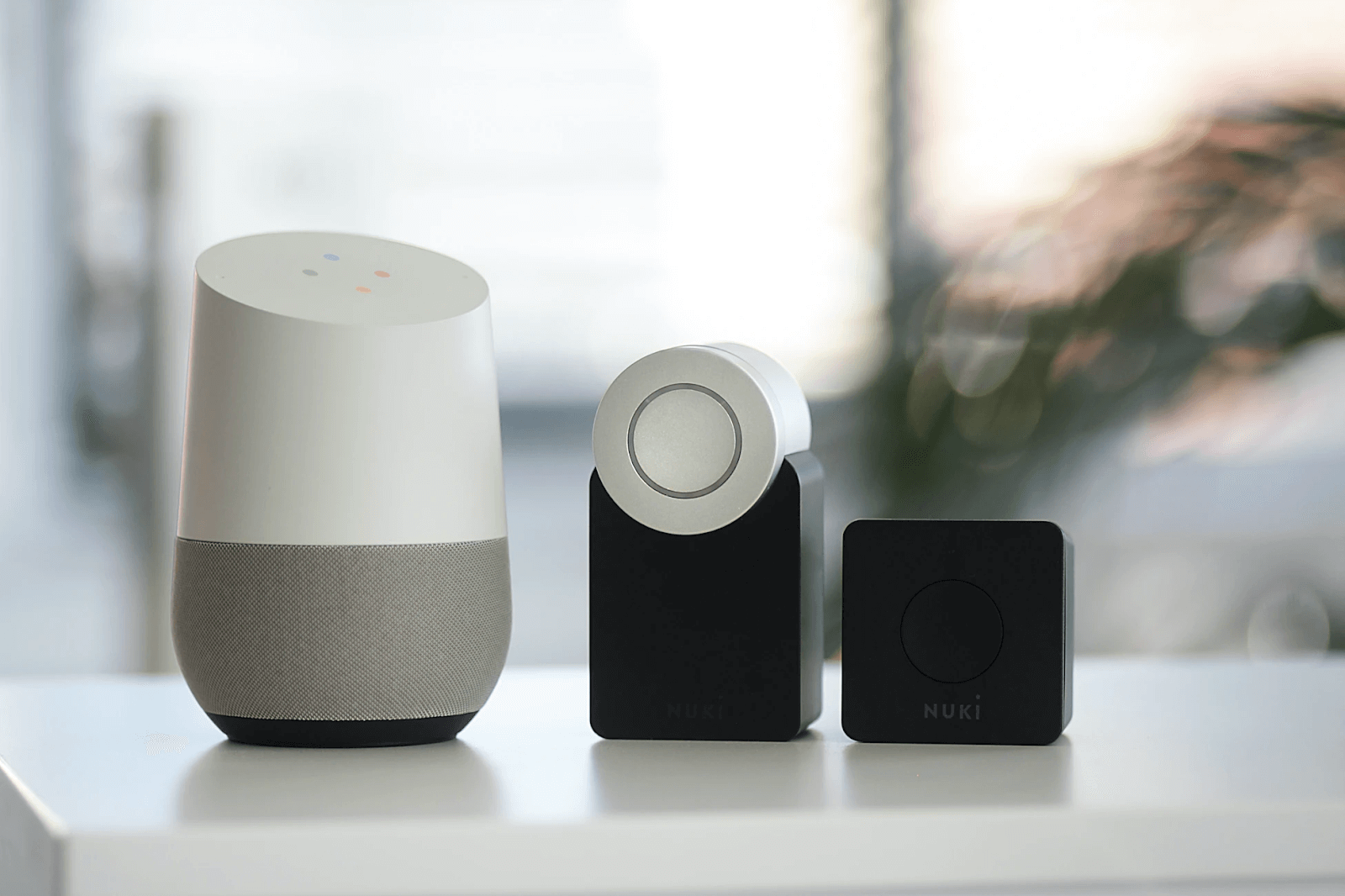 google home and other smart devices on a white surface with an out of focus background