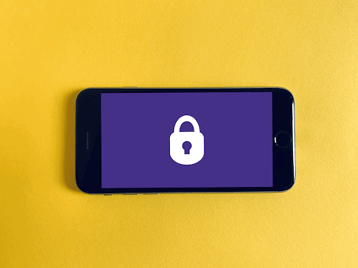 image of a black iphone 8 on a yellow surface with a purple screen and a white lock icon