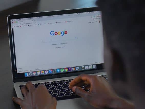 person typing something on Google Search on their laptop