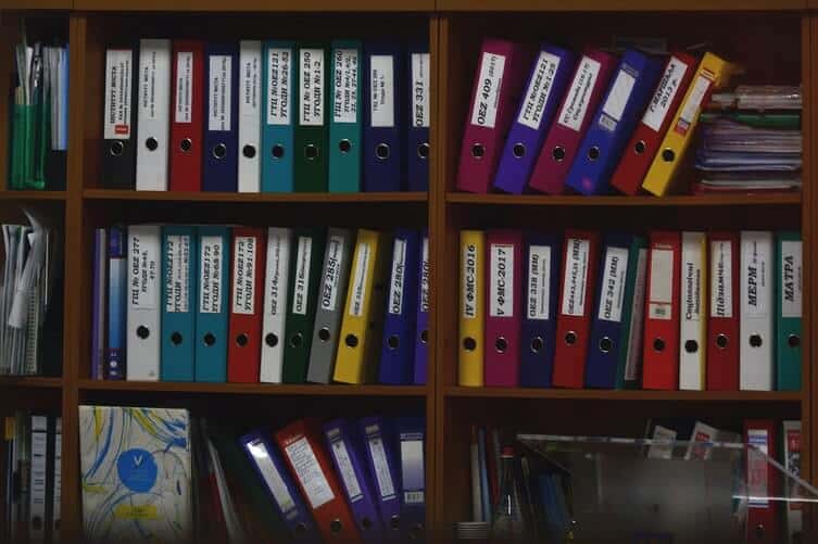 Multi-colored labeled folder on a wooden file cabinet shelf