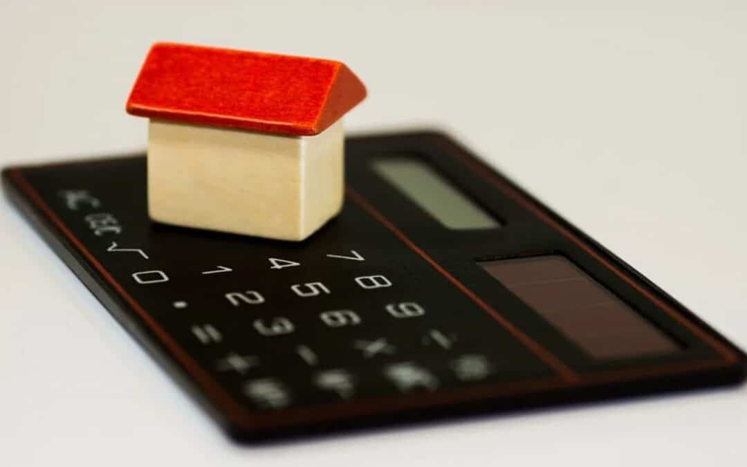 Red toy monopoly house on a calculator with a white background, portraying refinance opportunities